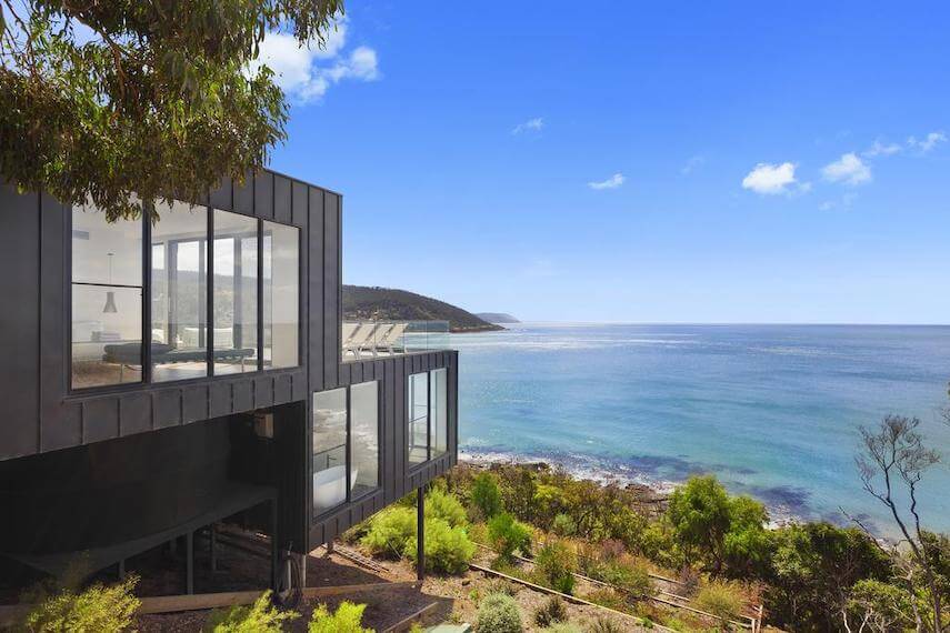 Side view of the multi story Cape Wye Holiday Home built into the hillside overlooking the ocean