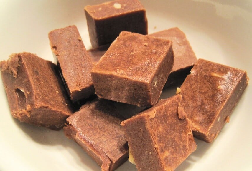 Squares of fudge piled up on a white surface