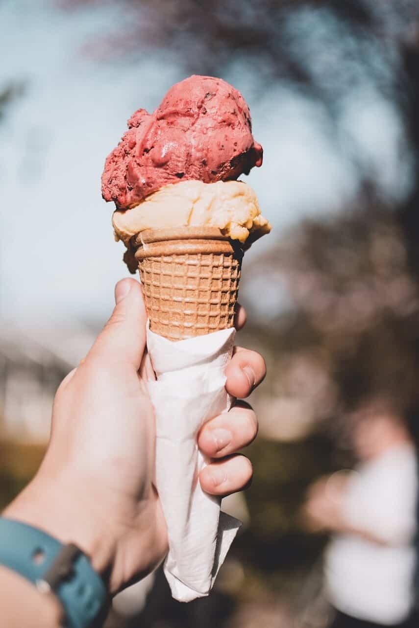 in focus hand holding a cone of ice cream