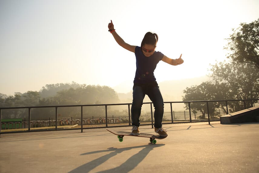 Woman on a skateboard with her arms in the air at Lorne Skate Park