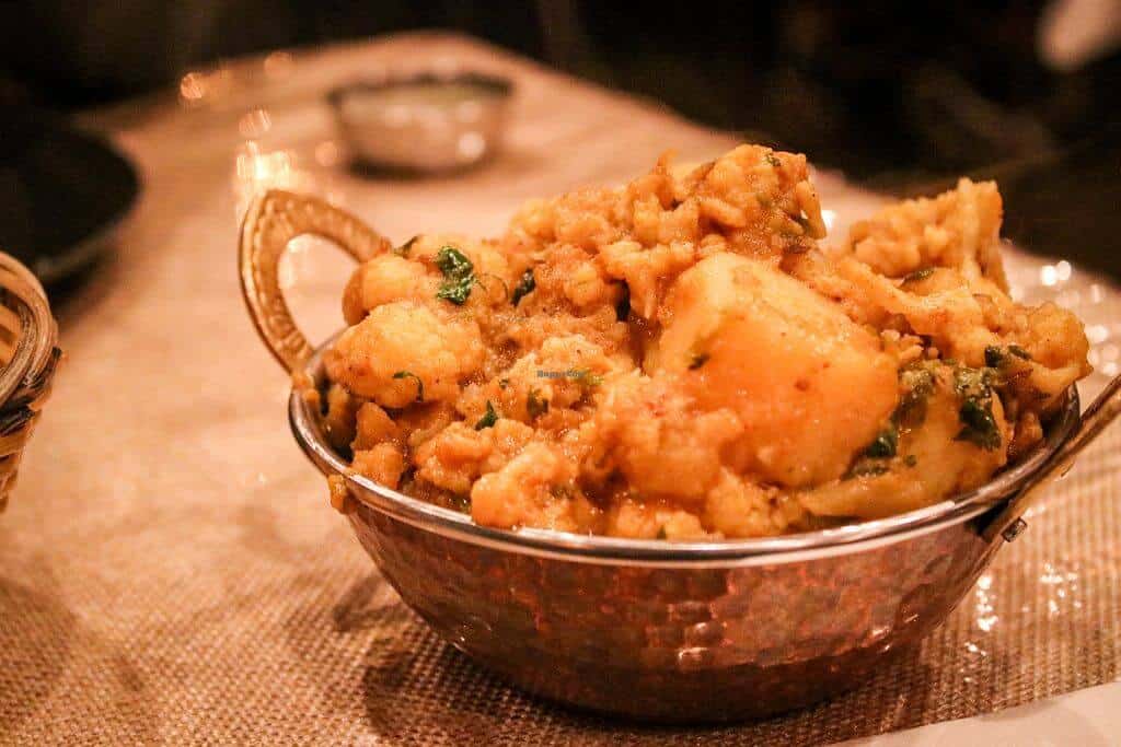 Curry in a metal bowl on a wooden table at Masala Bay Apollo Bay