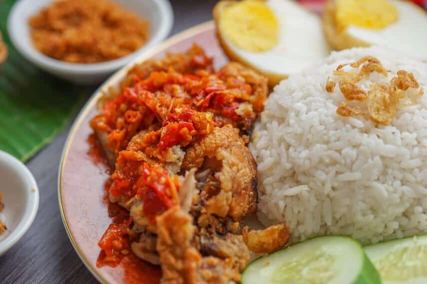 Chinese Chicken & Rice on a plate with cucumber and a boiled egg sliced in half