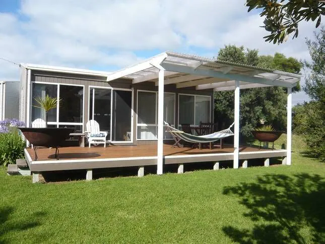 White wooden Home with deck in a green garden at By The Sea Aireys Inlet